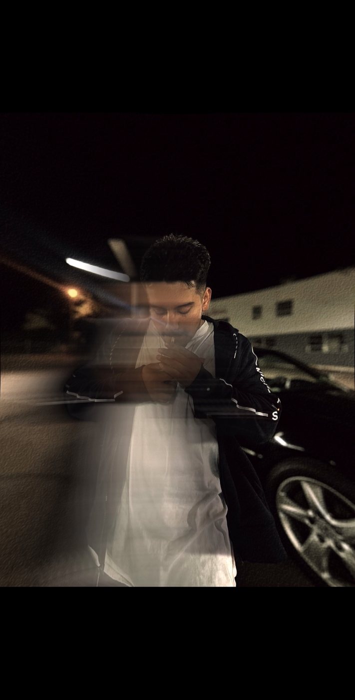 Belinskii leaning on a car at night, motion-blur portrait