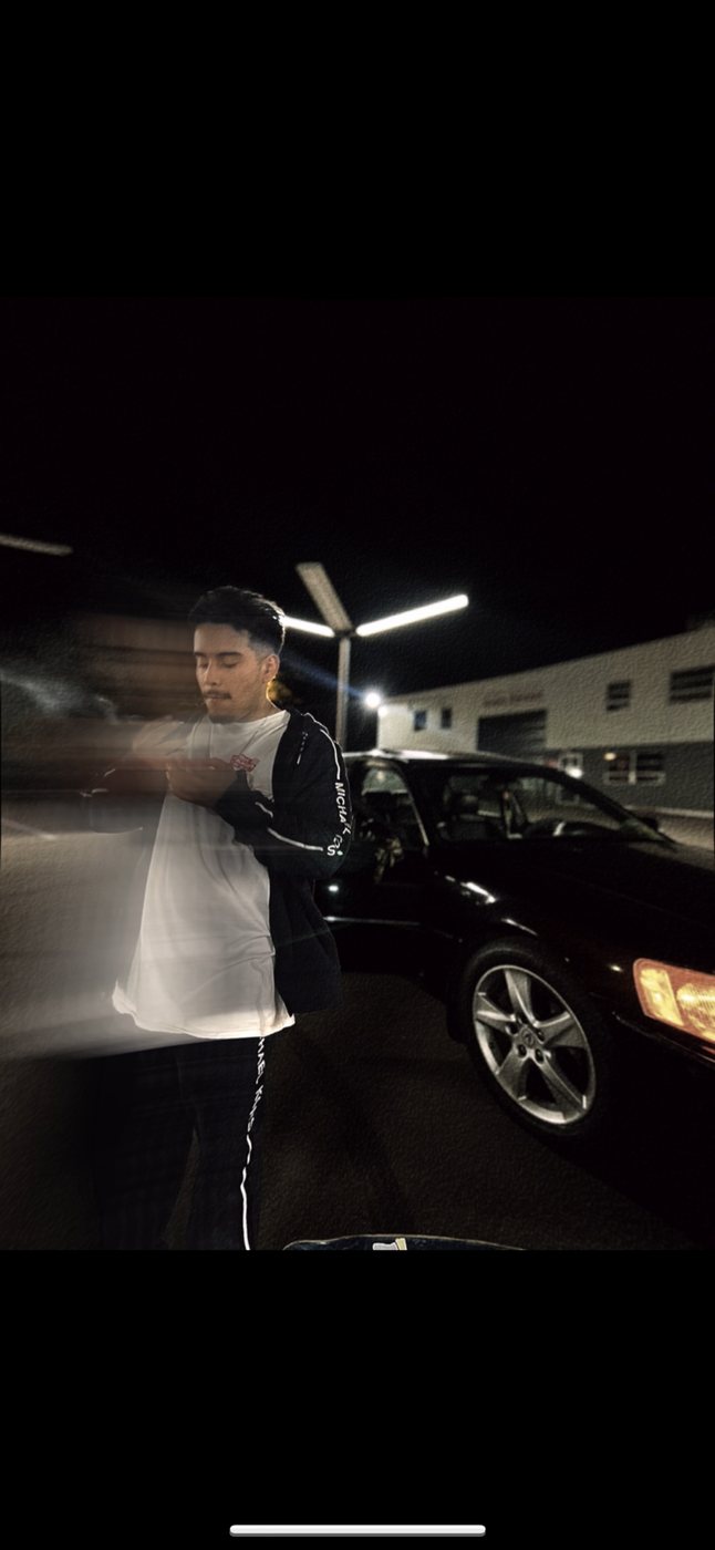 Belinskii by a black car under a parking lot light at night