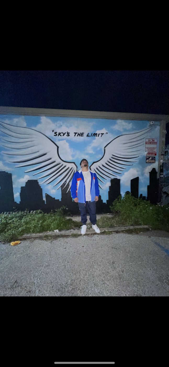 Belinskii in front of a Sky's the Limit angel-wings mural
